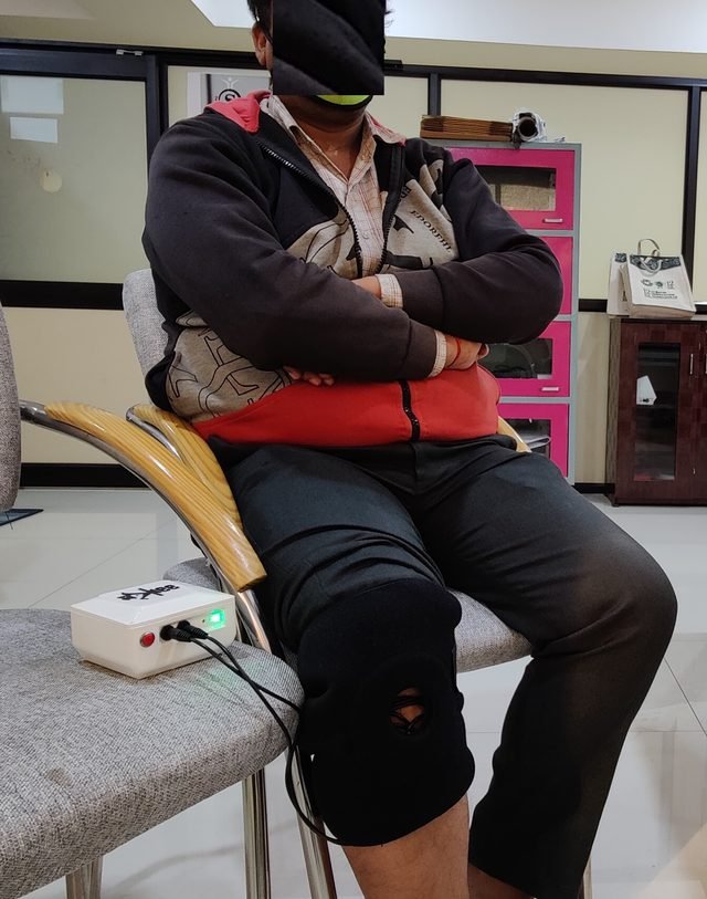 A participant seated with the SwaKnee applicator on the knee during a study session (identity obscured)