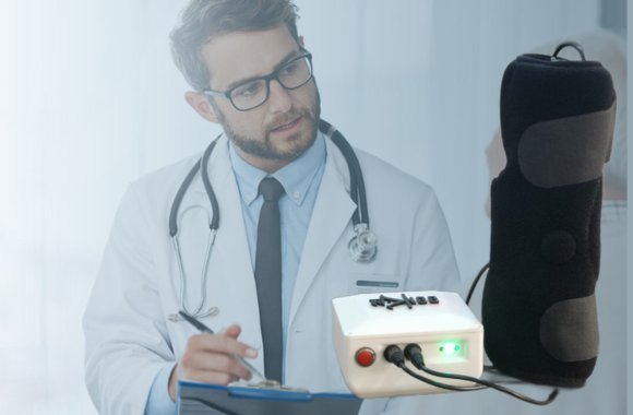 A clinician holding the SwaKnee control module and knee applicator